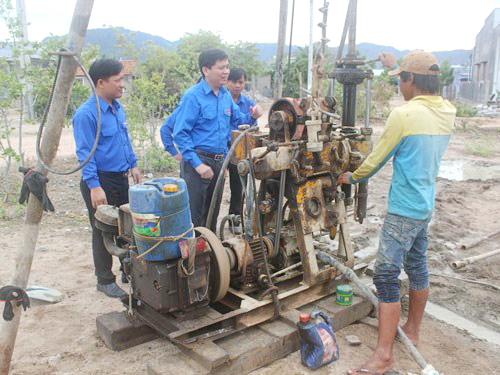 Anh Nguyễn Long Hải (áo xanh, đứng giữa) động viên thanh niên khoan giếng ở thôn Khánh Tân, xã Nhơn Hải - Ảnh: Thiện Nhân
